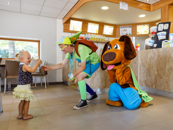 Een klein meisje geeft een high-five aan de medewerker van het animatieteam en de Molecaten-mascotte in de snackbar van Park De Flaasbloem.