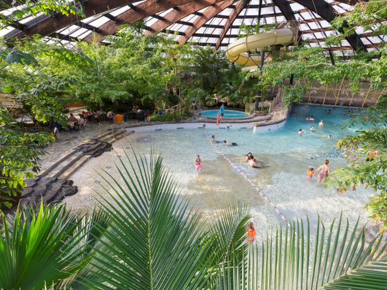 Overzicht van het golfslagbad in de tropische zwemparadijs Aqua Mundo van Center Parcs De Huttenheugte, waar mensen genieten van de golven.