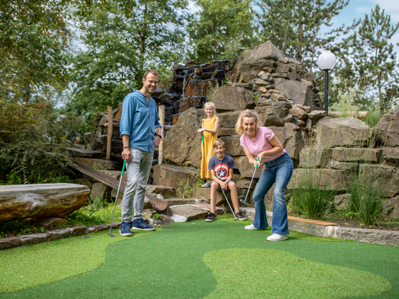 Een gezin met twee kinderen speelt een potje Adventure Golf op de avontuurlijke midgetgolfbaan van Center Parcs De Huttenheugte.