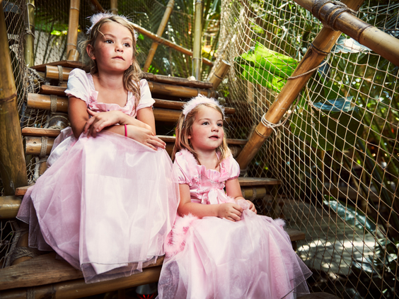 Twee meisjes in roze prinsessenjurken zitten op een houten trap tijdens de 'Wannabe een Prinses' activiteit bij Center Parcs De Huttenheugte.
