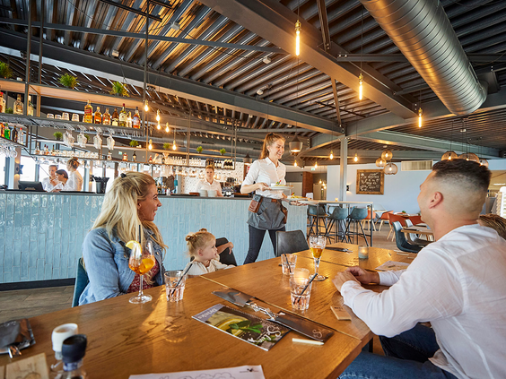 Een gezin bestelt drankjes bij de serveerster in het sfeervolle familierestaurant Grillo op Recreatiepark De Leistert.