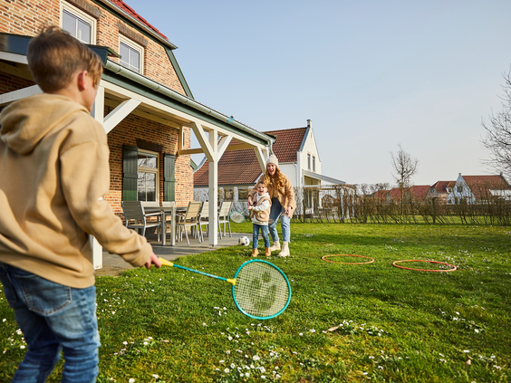 Kinderen spelen badminton op het grasveld voor een vakantiehuis bij De Leistert