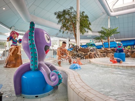 Kinderen spelen in het kinder-doe-bad van het subtropisch zwembad op Recreatiepark De Leistert, met een vrolijke paarse octopus en andere waterspeeltoestellen.