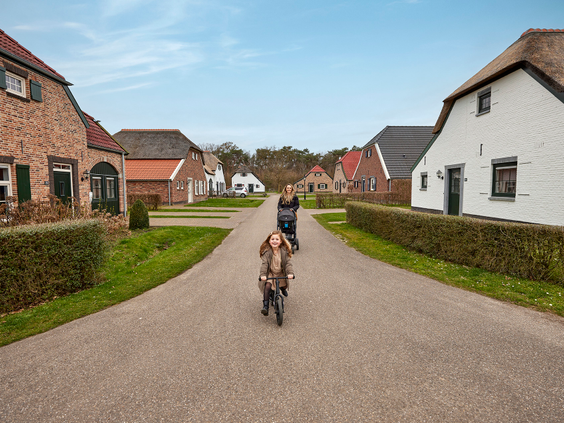 Moeder en klein meisje op een fiets lopen een rondje over het vakantiepark.