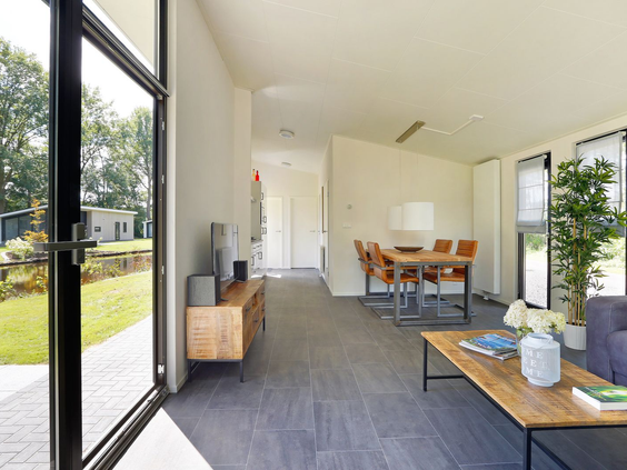 Lichte woonkamer in een vakantiehuis op De Lochemse Berg, waarbij de openstaande deuren de leefruimte verbinden met het terras en de tuin.