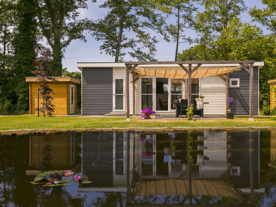 Twee moderne vakantielodges direct aan het water op Vakantiepark De Lochemse Berg, weerspiegeld in de vijver.