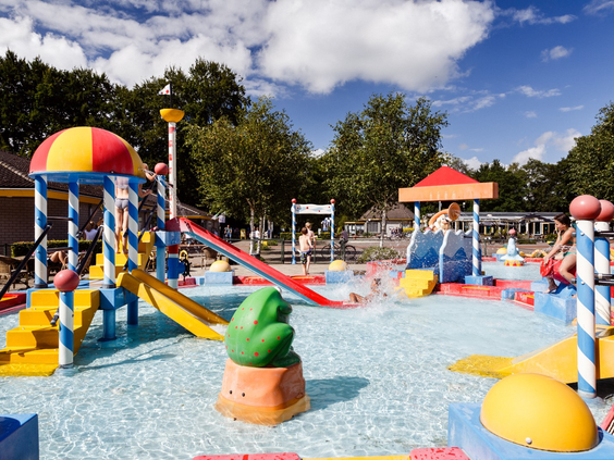 De kleurrijke waterspeeltuin (spraypark) van RCN de Roggeberg in Friesland, vol met glijbanen, sproeiers en speeltoestellen voor kinderen.