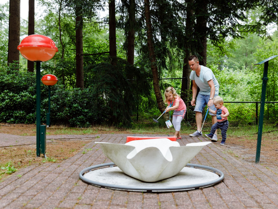Een vader met zijn kinderen bij een uitdagende hindernis op de avontuurlijke midgetgolfbaan van RCN de Roggeberg.
