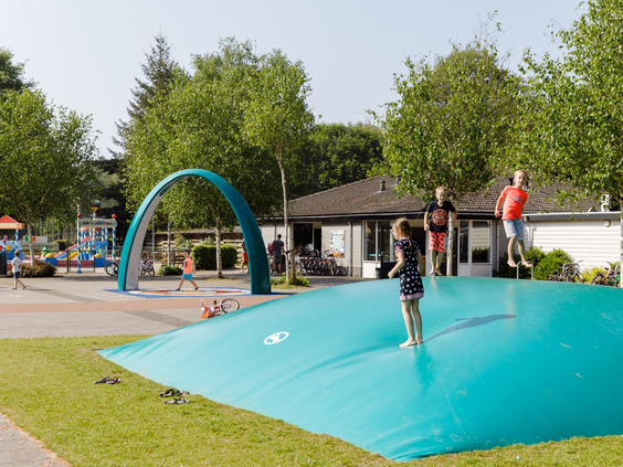 Kinderen die zich uitleven en hoog springen op de grote airtrampoline (luchtkussen) op RCN de Roggeberg, een populaire speelplek.