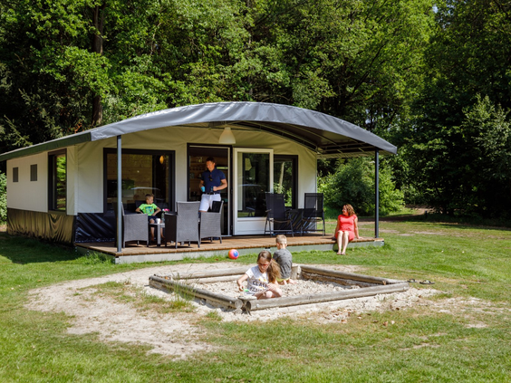 Een moderne bungalow op RCN de Roggeberg met een eigen zandbak direct voor het terras, waar kinderen heerlijk kunnen spelen.