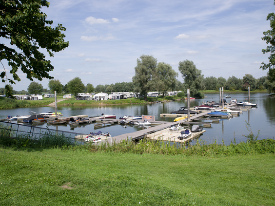 De jachthaven van Recreatiepark De Scherpenhof, met diverse boten aangemeerd in het water van de IJssel.