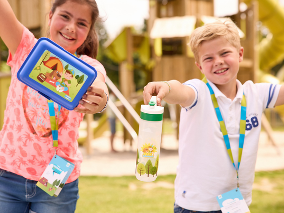 Blije kinderen tonen trots hun Kruimelpad-lunchbox en drinkbeker van het animatieteam op vakantiepark RCN de Schotsman.