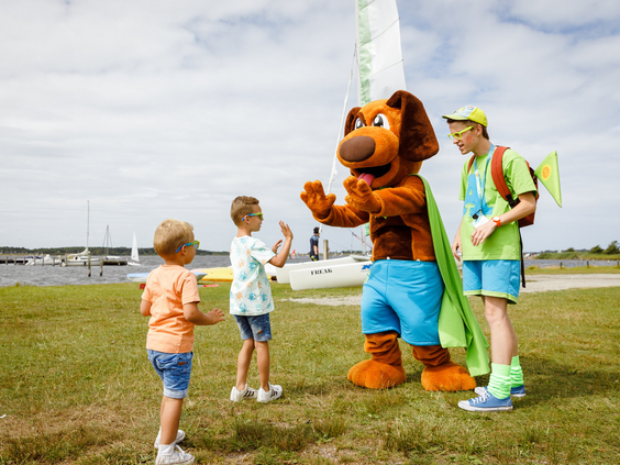 Kinderen geven een high-five aan mascotte Alex Avontuur bij het Veerse Meer op vakantiepark RCN de Schotsman.