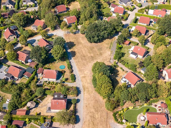 Luchtfoto van de verspreid liggende vakantiehuizen op De Tolplas, met rode daken en veel groen tussen de woningen.