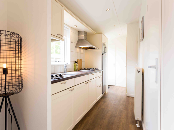 Een moderne, volledig ingerichte keuken in een vakantiehuis op De Wielerbaan, met kookplaat, afzuigkap en gootsteen.