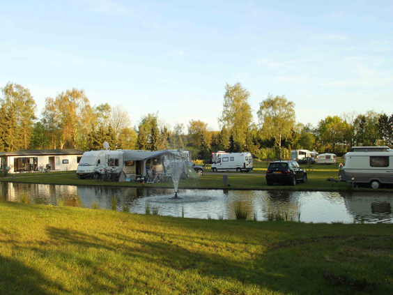 Overzicht van de kampeerplaatsen voor caravans en campers rondom de vijver op de camping van De Wielerbaan.