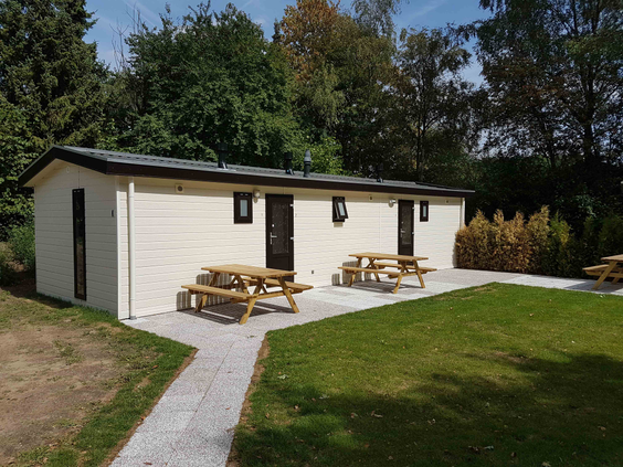 Een groepsaccommodatie op vakantiepark De Wielerbaan met meerdere picknicktafels buiten op het terras, ideaal voor grote gezinnen of groepen.