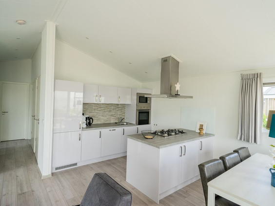 De strakke, witte, open keuken met kookeiland in een modern vakantiehuisje (lodge) op De Wije Werelt.