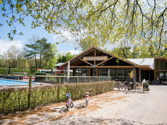 Het restaurant van De Wije Werelt met een groot houten terras, gelegen naast de buitenspeeltuin en het zwembad op de Veluwe.