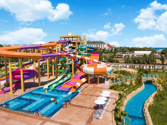 Overzicht van het grote waterpark van Delphin BE GRAND Resort in Lara, met veel kleurrijke glijbanen en een lazy river.