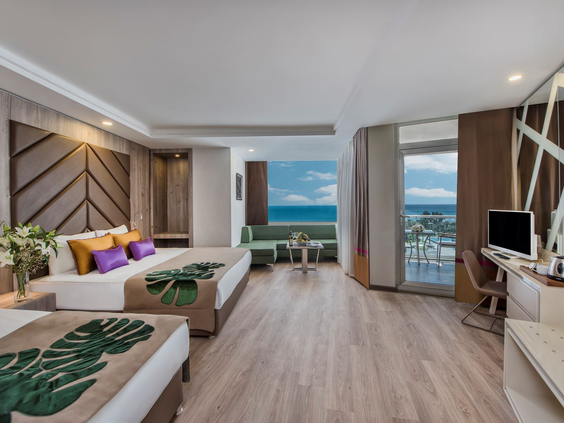 Ruime familiekamer met meerdere bedden, een zithoek en een balkon met zeezicht bij Delphin BE GRAND Resort.
