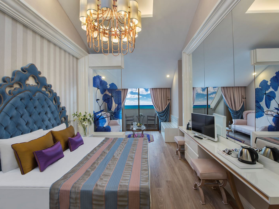 Een zeer luxe en thematisch ingerichte suite met een blauw hoofdeinde en chique meubels in Delphin BE GRAND Resort.