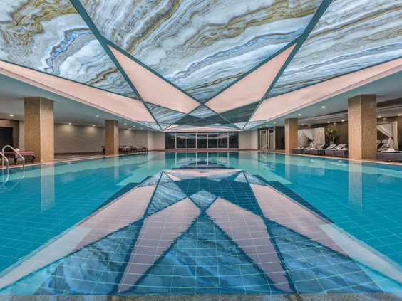 Het luxe binnenzwembad van Delphin BE GRAND Resort met een prachtig ontworpen plafond.