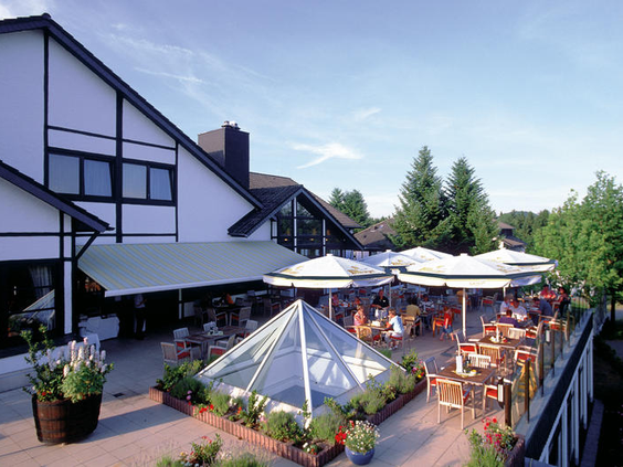 Het zonnige terras van het restaurant van Dorint Vakantiepark Daun, met uitzicht op de groene omgeving van de Eifel.