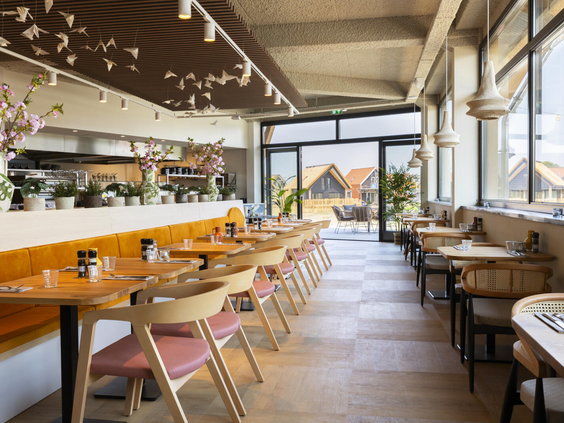 Het lichte en modern ingerichte restaurant Ninety op Dormio Resort Nieuwvliet-Bad, met houten tafels en comfortabele stoelen.
