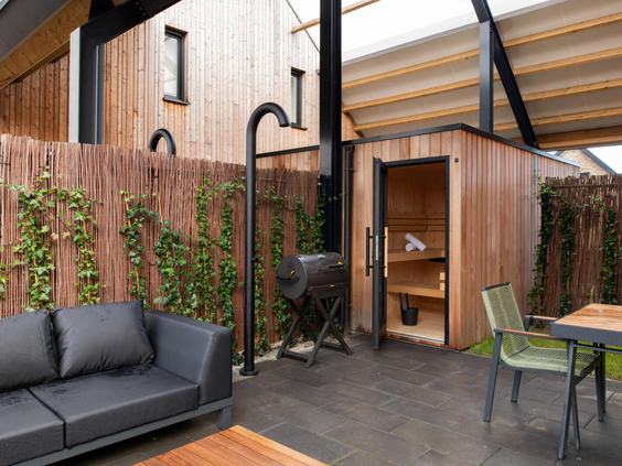 Luxe terras van een wellness-vakantiewoning op Dormio Resort Nieuwvliet-Bad, met een privé buitensauna, buitendouche, barbecue en loungehoek.