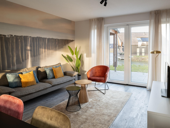 Lichte, modern ingerichte woonkamer in een vakantiehuis op Dormio Resort Nieuwvliet-Bad, met openslaande deuren naar de tuin.
