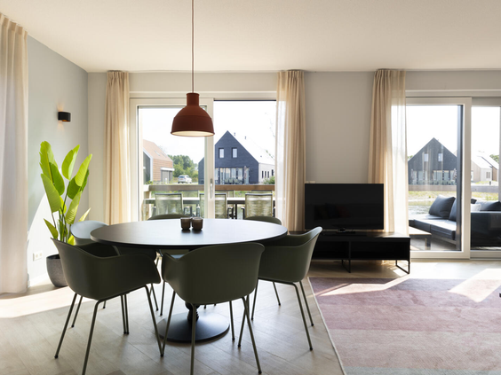 Modern ingerichte eethoek met een ronde tafel in een lichte vakantiewoning op Dormio Resort Nieuwvliet-Bad, met uitzicht op buiten.