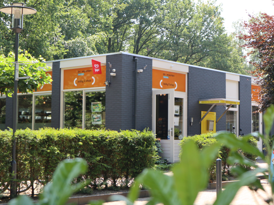 Het moderne, kleurrijke receptiegebouw van Droompark Hooge Veluwe, waar gasten worden verwelkomd op het vakantiepark.