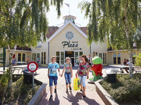 Een gezin loopt hand in hand weg van de Duinrell Plaza, het centrale horeca- en entertainmentgebouw op het vakantie- en attractiepark.