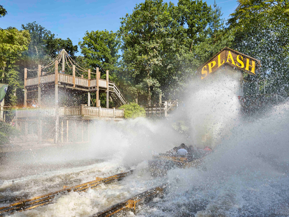 Close-up van de attractie de Splash in Duinrell, waarbij een bootje een enorme golf water creëert die op de camera afkomt.
