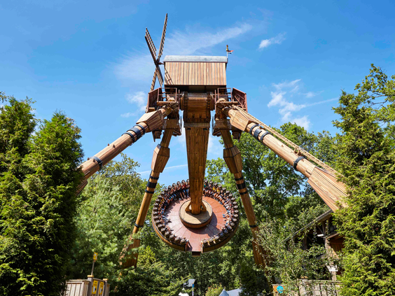De attractie de Mad Mill in attractiepark Duinrell, een grote houten molen die als een zweefmolen met bezoekers hoog door de lucht zwaait.