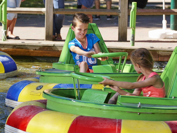 Twee kinderen in kleurrijke botsbootjes op het water in attractiepark Duinrell, waarbij ze elkaar proberen te botsen.