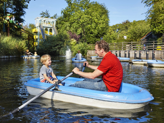 Een vader en zoon roeien samen in een blauw bootje op de vijver van Duinrell op een zonnige dag.