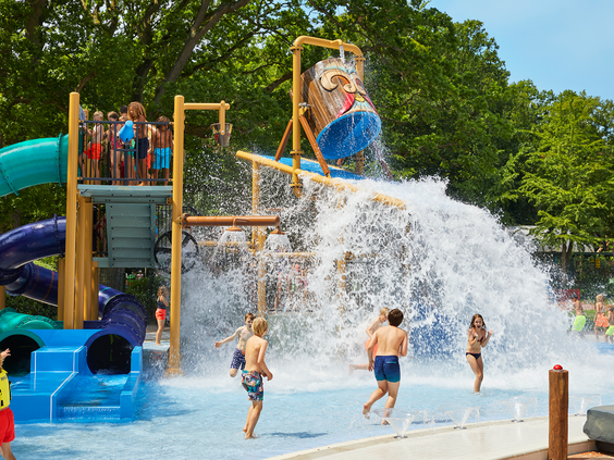 Een grote waterton kiept om en stort een enorme golf water over spelende kinderen in de waterspeeltuin van het Tikibad op Duinrell.