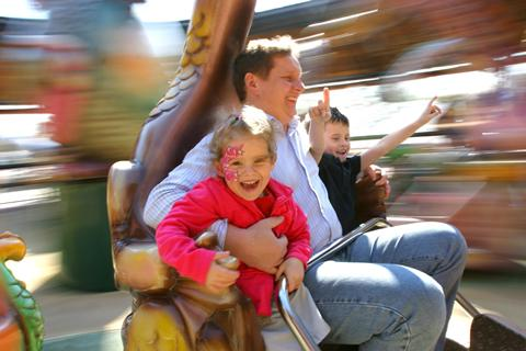 Een vader met zijn lachende kinderen in een snelle, draaiende attractie in attractiepark Europa-Park