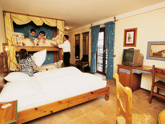 Een familie heeft plezier met een kussengevecht in een Spaanse themakamer van Hotel El Andaluz, met kinderen in een uniek stapelbed dat lijkt op een poppenkast.