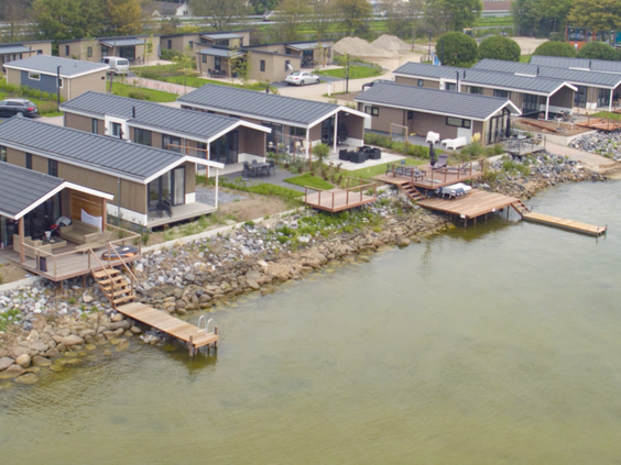 Luchtfoto van de moderne vakantiehuisjes met privé aanlegsteigers aan het water op EuroParcs Markermeer.