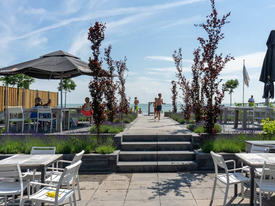 Een sfeervol pad met trappen leidt naar het strand en de beachclub van EuroParcs Markermeer, met uitzicht op het water.