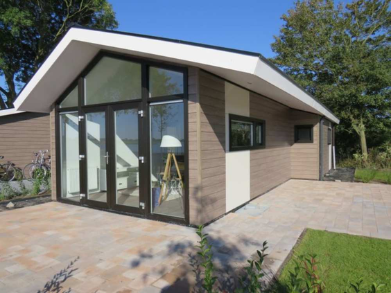 De buitenkant van een moderne, duurzame vakantiewoning op EuroParcs Markermeer, met grote glazen deuren die uitkomen op het terras.