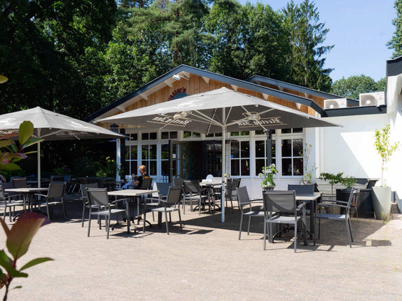 Het zonnige terras van het restaurant met comfortabele stoelen en parasols op EuroParcs Resort De Utrechtse Heuvelrug.