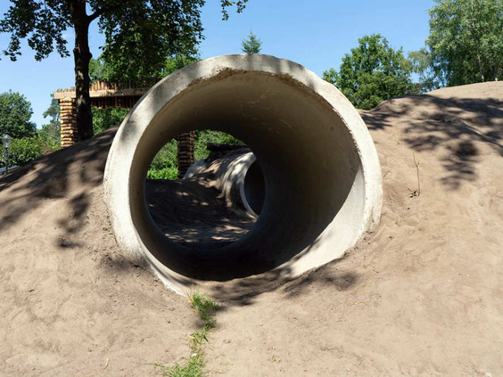 Een kind dat door een betonnen tunnel kruipt in de avontuurlijke speeltuin van het vakantiepark.