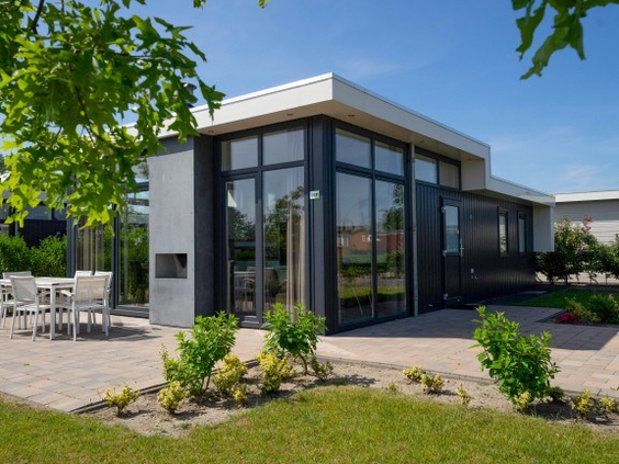 De buitenkant van een luxe, moderne vakantiewoning met grote ramen en een ruim terras op EuroParcs Resort Limburg.