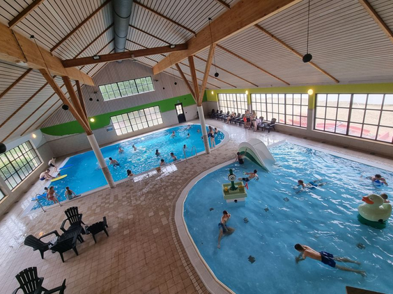 Overzicht van het overdekte zwemparadijs van EuroParcs Resort Limburg, met een recreatiebad, glijbaan en spelende gasten.