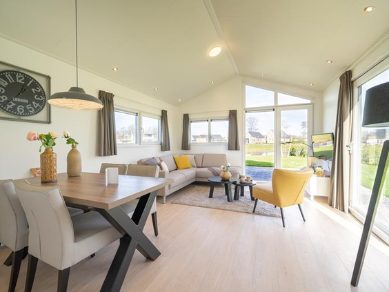 De lichte en moderne woonkamer van een vakantiewoning op EuroParcs Resort Limburg, met een ruime zithoek en eettafel.