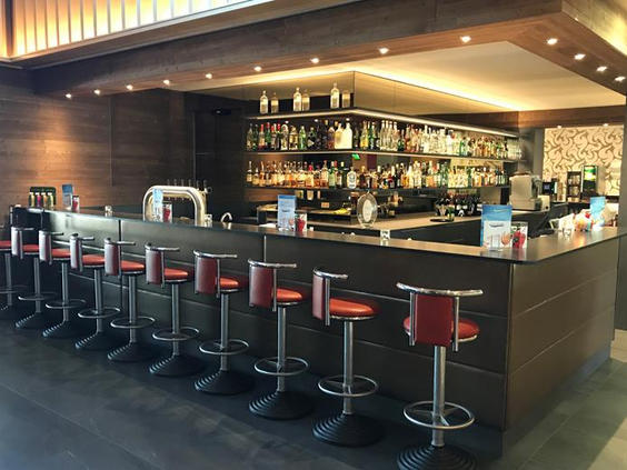 De sfeervol verlichte hotelbar van het FAIR Resort met comfortabele barkrukken, ideaal voor een drankje in de avond.